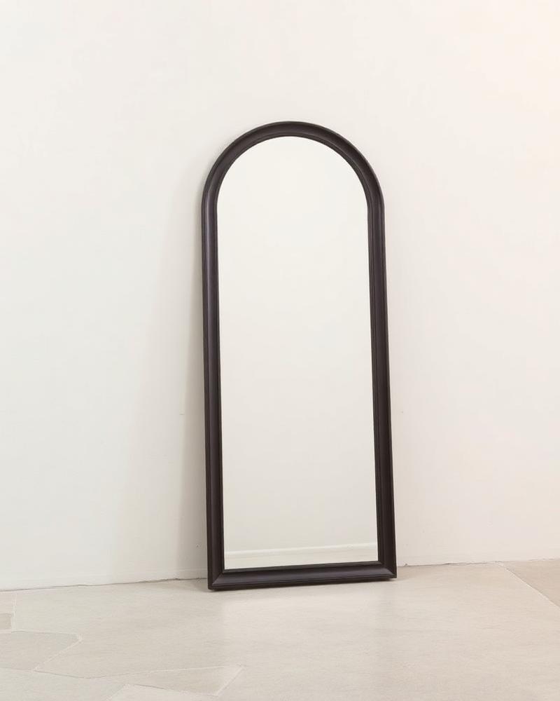Selene oversized arch floor mirror with a slim dark frame leaning against a wall